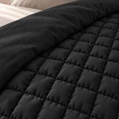 Detail van de kleine puffy vakjes en de gladde, effen onderkant van het zwarte dekbed.